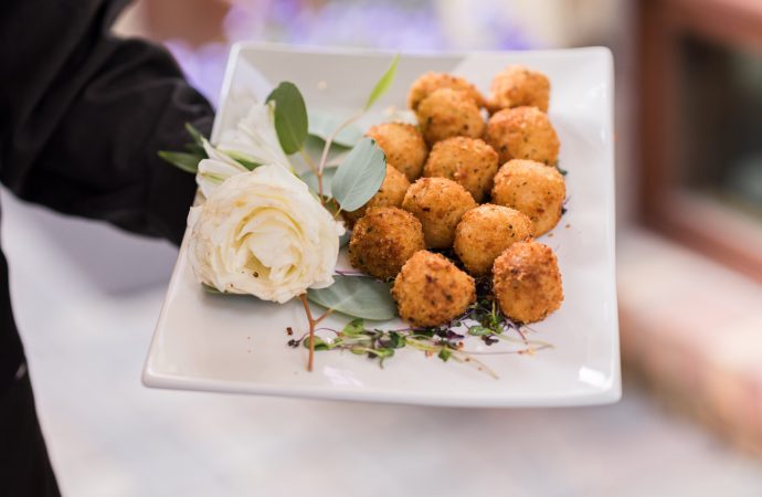 Server with plate of appetizers with a large, white flower decoration