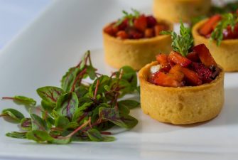 Strawberry fruit cups inside of baked pastry with leafy garnish