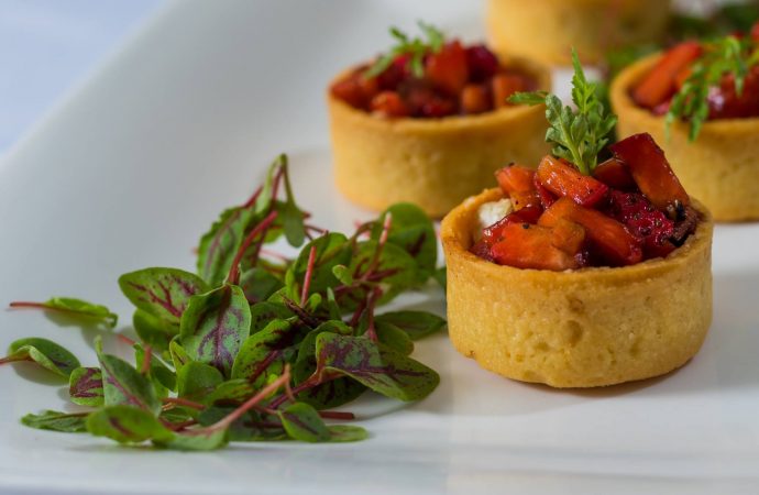 Strawberry fruit cups inside of baked pastry with leafy garnish