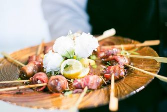 Server holding out plate of individual appetizers