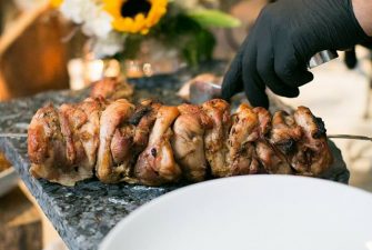 Chef prepares to cut a skewer of roasted meat