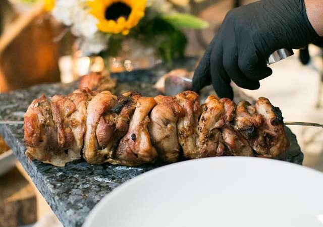 Chef prepares to cut a skewer of roasted meat