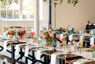 Long, wooden benches decorated with colorful flowers and drinking glasses