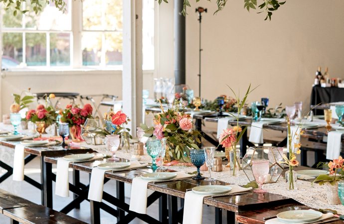 Long, wooden benches decorated with colorful flowers and drinking glasses