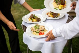 Servers prepare serving a plated meal
