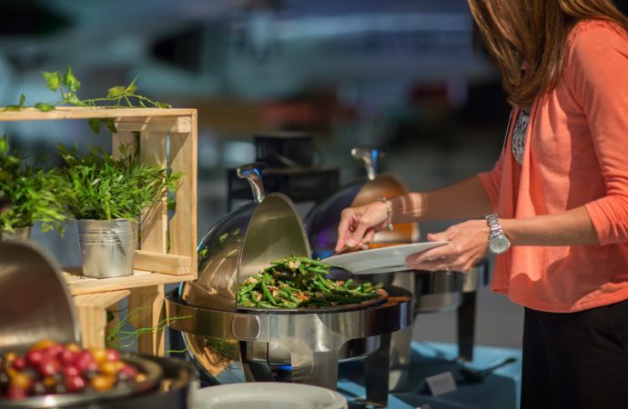 Woman at buffet display dishing out fresh green beans