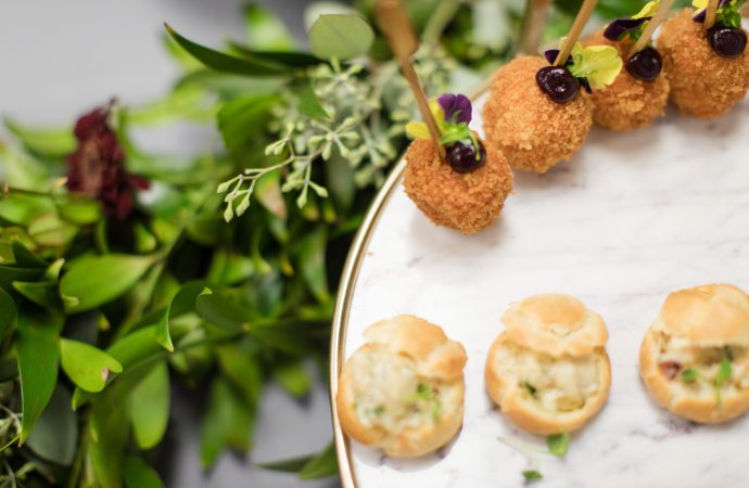 Plate of individual appetizers on display over a leafy green decoration