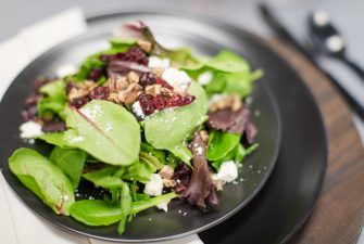 Plated salad with greens, nuts, and cranberries