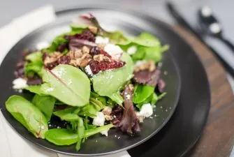 Plated salad with greens, nuts, and cranberries