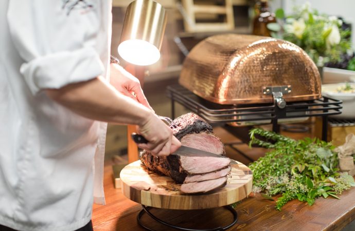 server cutting meat on a board at an event