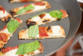 Bakes slices of flatbread with cheese and basil garnish