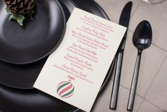 Holiday themed menu set on black place setting