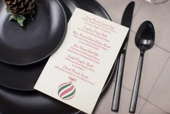 Holiday themed menu set on black place setting