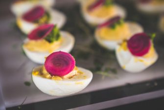 plate of deviled eggs with red garnish