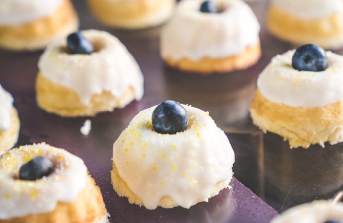 Tray of small, frosted deserts with creme and blueberry topping