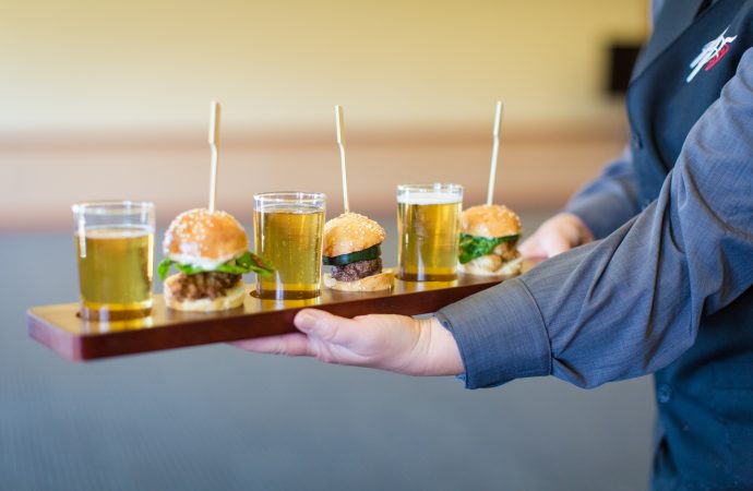 Server holding plate of burgers and beer