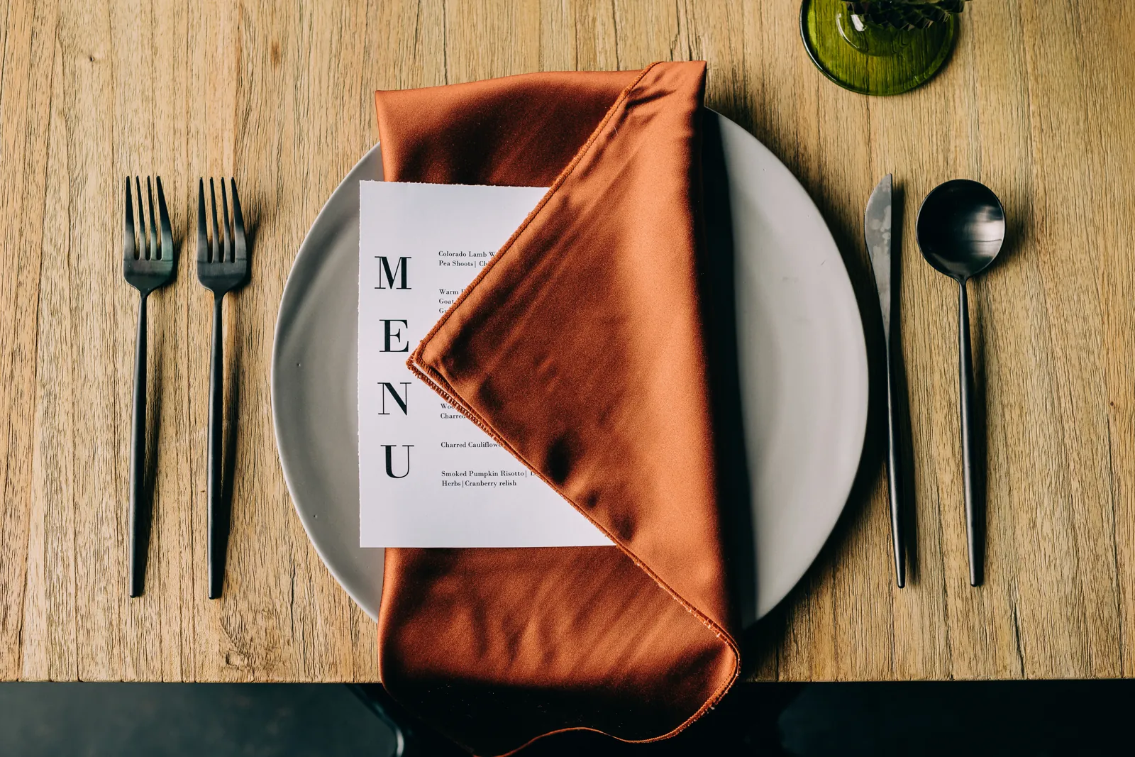 place setting with a menu tucked into an orange napkin