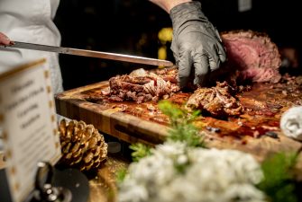 Chef at carving station with tender beef on a large, wooden cutting board