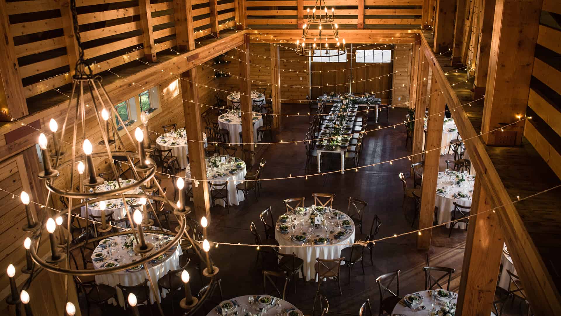 Rustic interior looking down from balcony with chandelier and round tables