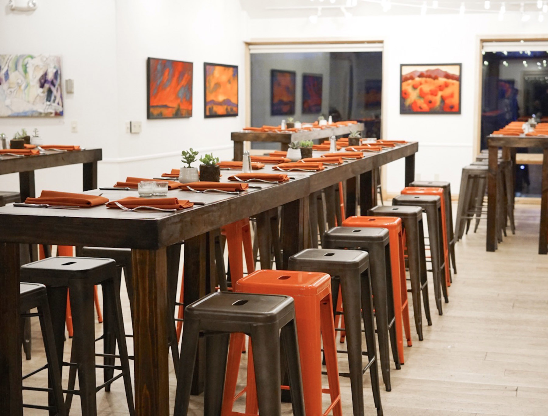 High top table with orange and brown stools in an open gallery
