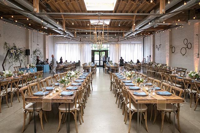 Rows of tables decorated for a wedding underneath a skylight in the wooden roof