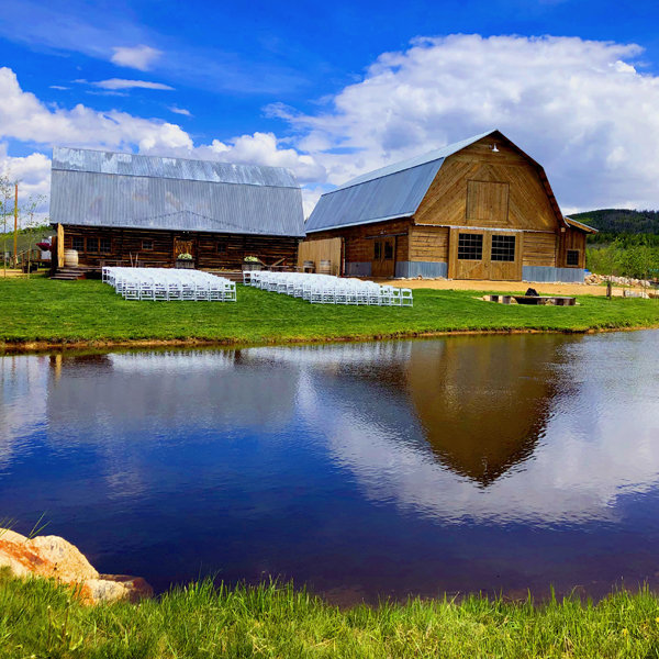 Large brown barn and white chairs on reflective blue lakefront