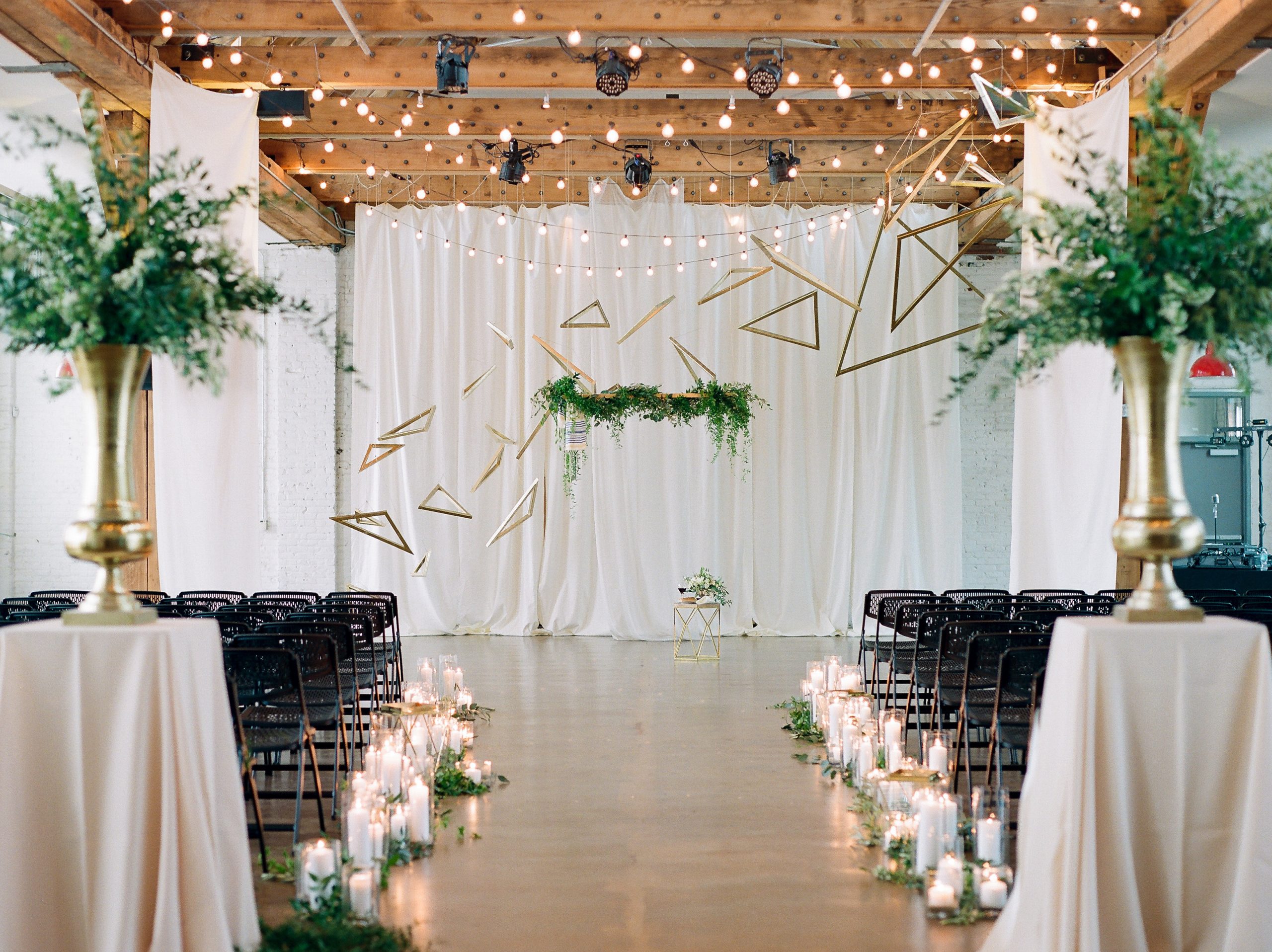 Interior wedding scene with white backdrop and flanking palms