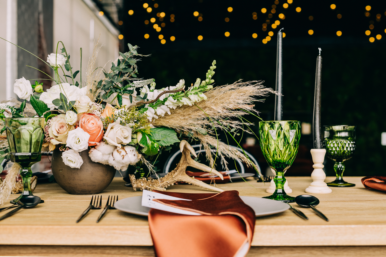 head on shot of large floral arrangement behind a place setting with an orange napkin and menu