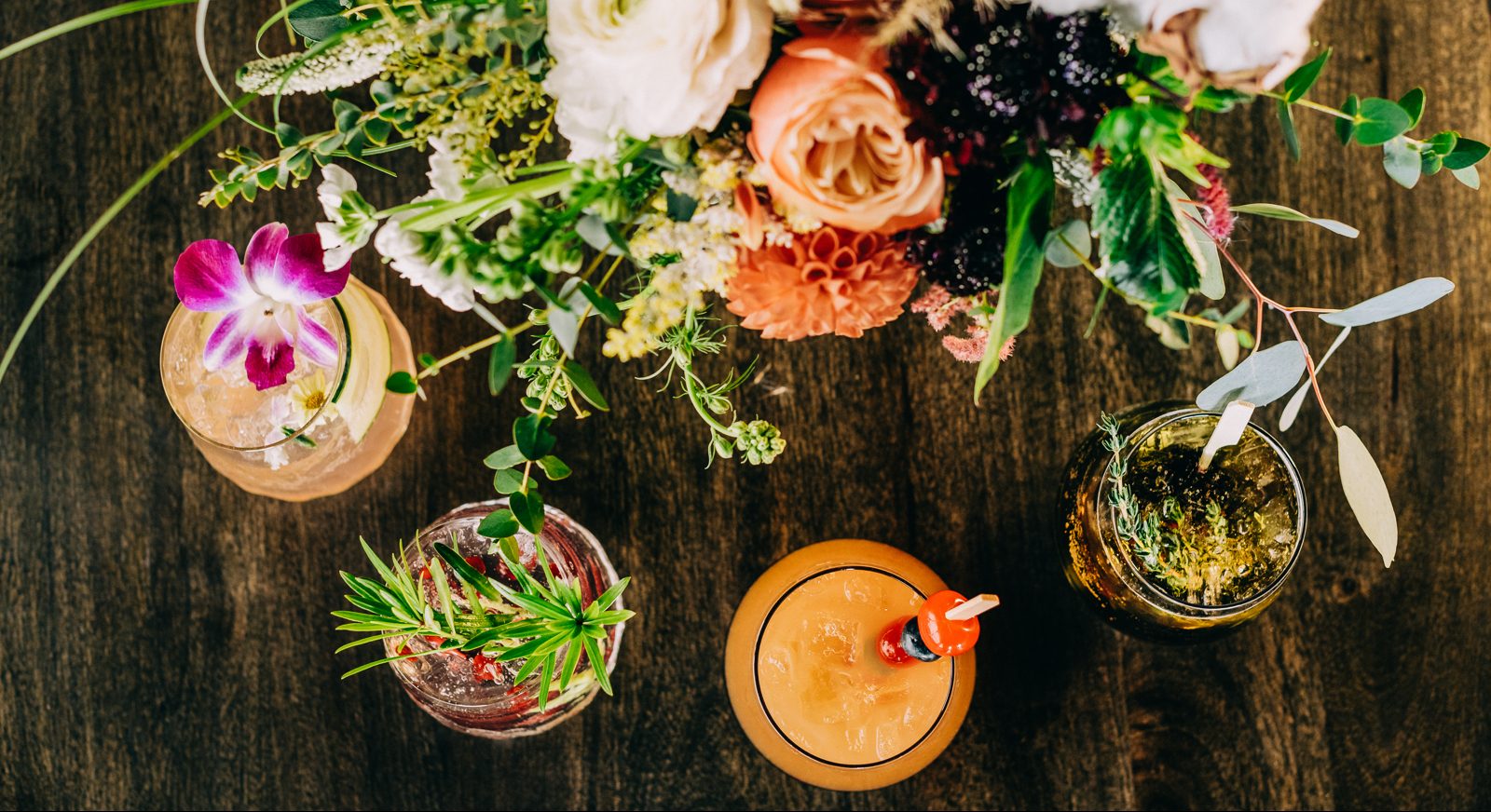 top down view of large floral arrangement and four specialty drinks