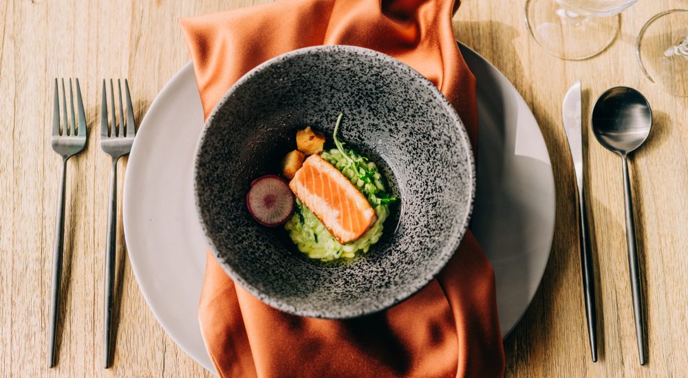 overhead shot of grey bowl, with brightly colored food, on top of an orange napkin