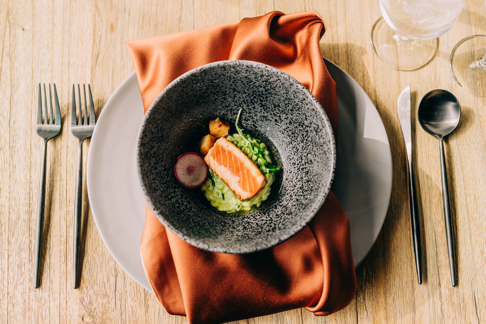 overhead shot of grey bowl, with brightly colored food, on top of an orange napkin