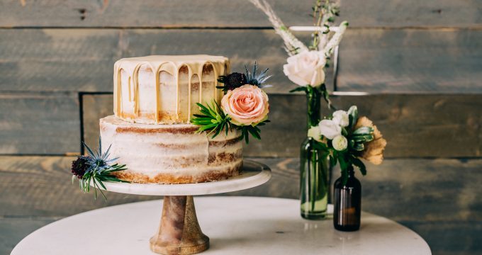 two tier cake decorated with flowers and two bouquets next to it