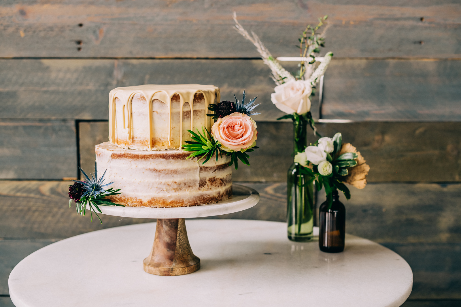 two tier cake decorated with flowers and two bouquets next to it