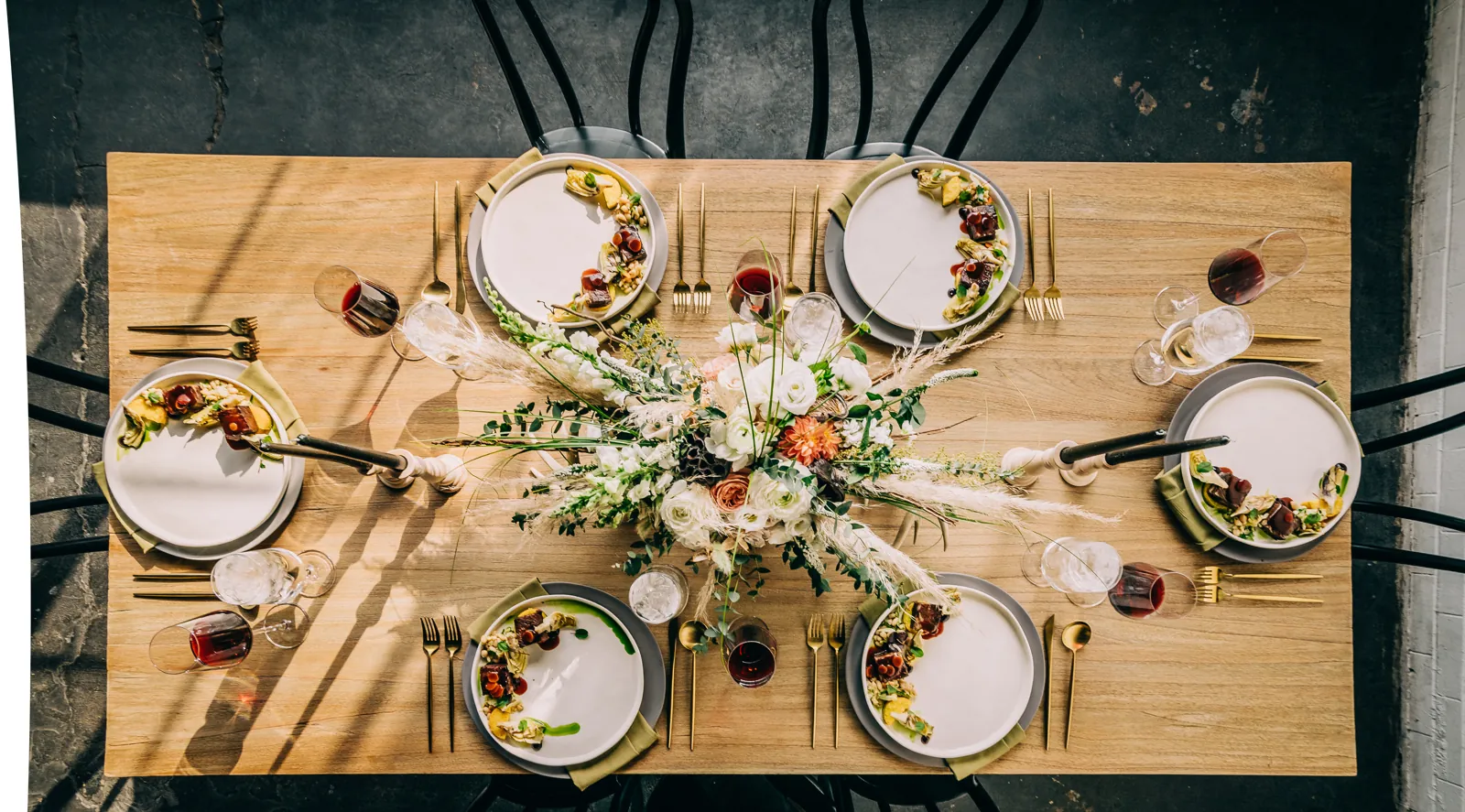 overhead shot of large floral arrangement, place settings and stylized meal