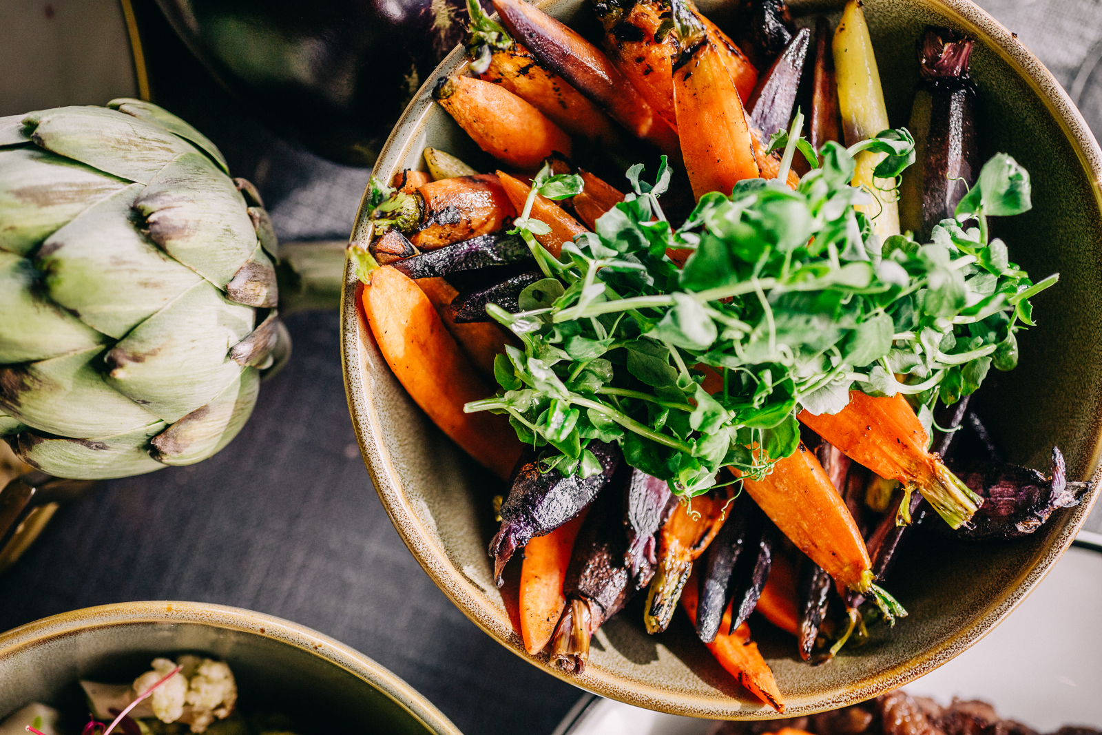 full artichokes and a salad of arugula and carrots