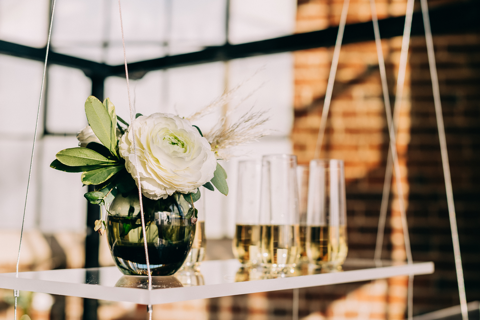 stemless champagne flutes on suspended table with rose in vase