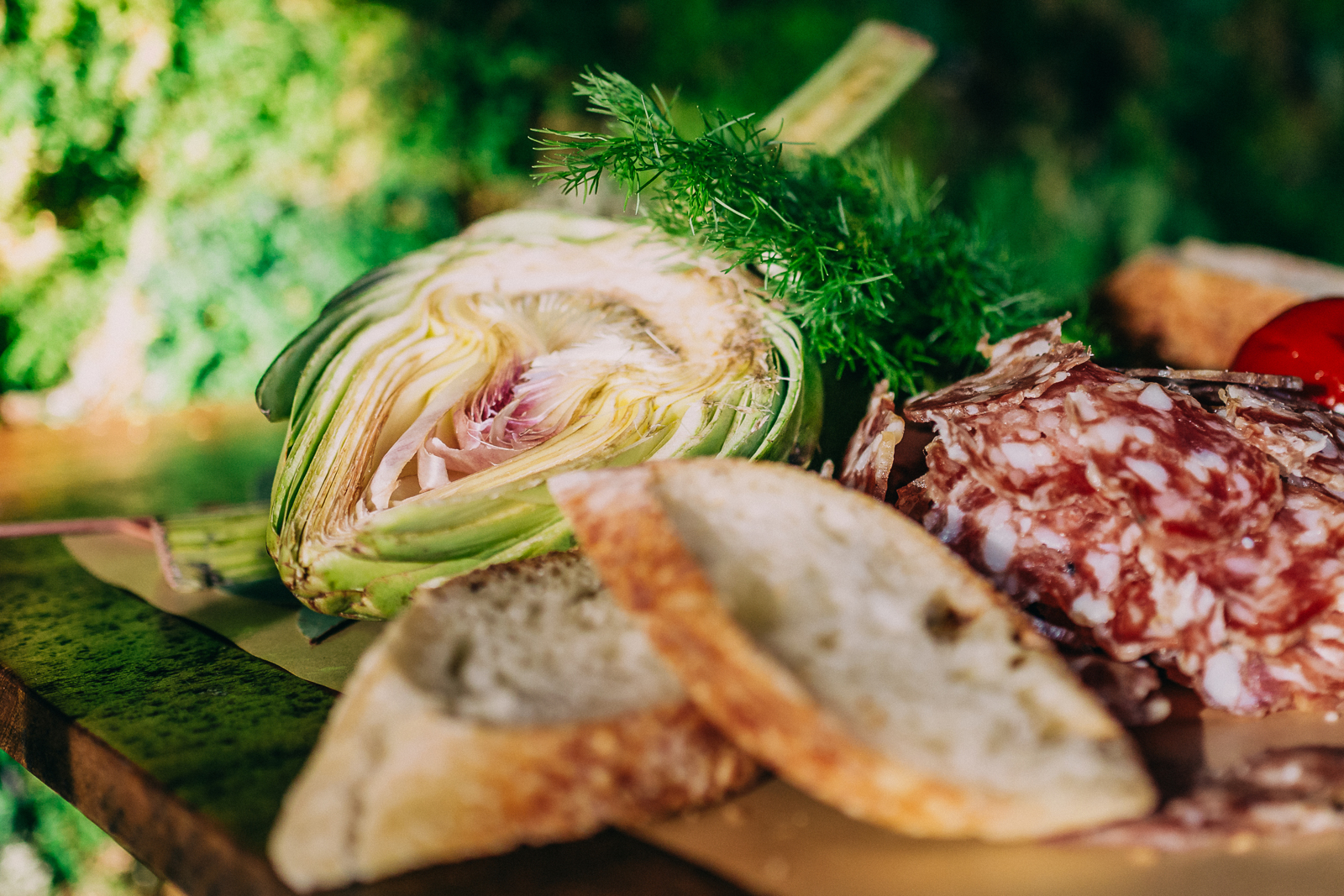 close up of halved artichoke, baguette and cured meat