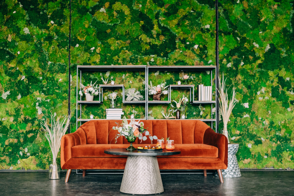 Orange couch in front of moss wall